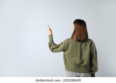 Young girl pointing on white background, back view. Space for text - Powered by Shutterstock