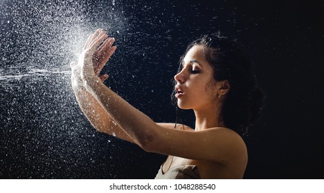 Young Girl Portrait And Splashing Water In Her Face. Beautiful Female Model On Black Background.