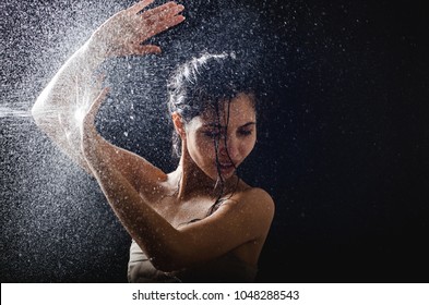 Young Girl Portrait And Splashing Water In Her Face. Beautiful Female Model On Black Background.