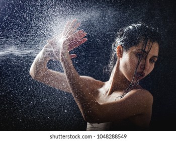 Young Girl Portrait And Splashing Water In Her Face. Beautiful Female Model On Black Background.