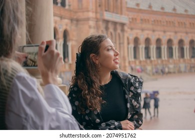 Young girl poses smiling while her friend takes a picture of her in Plaza of Spain in Seville to post on her social media.  - Powered by Shutterstock