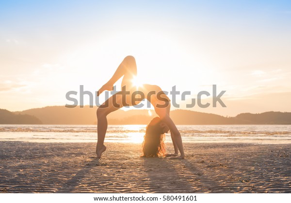 夕日にビーチでヨガを練習する若い女の子 美しい女性夏休み瞑想海に沈む海洋旅行 の写真素材 今すぐ編集