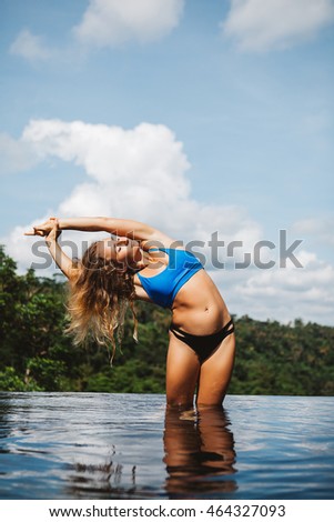 Young girl practicing yoga in the pool with jungle view during yoga retreat vacation in Bali