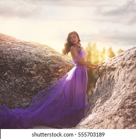 Young Girl In A Purple Dress On The Edge Of A Cliff