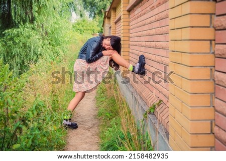 A young girl put her foot on a brick fence in the park