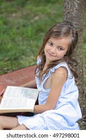 Young Girl Reading A Book Outside