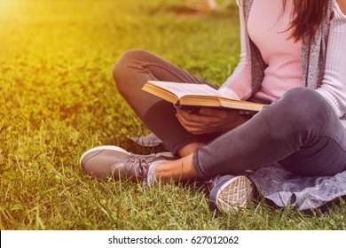 Young Girl Reading Book Outside Sitting On Green Grass In Park On Meadow. Read And Rest