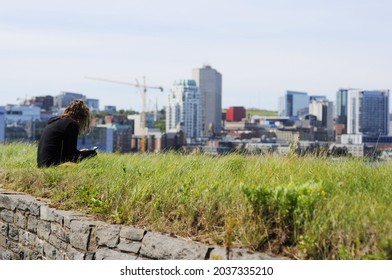 Young Girl Reading Tablet Outside In Summer