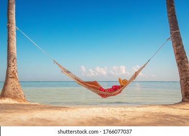 Young girl resting in a hammock under tall palm trees, tropical beach - Powered by Shutterstock