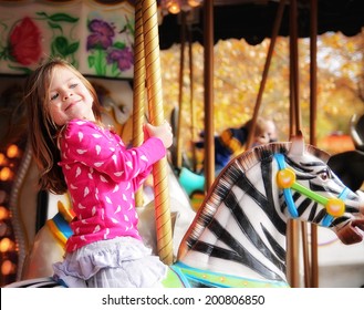 A Young Girl Riding On A Merry Go Round At The Zoo