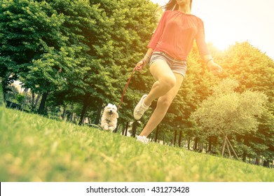 Young Girl Running With Her Dog. Puppy White Dog Is Running With It's Owner. Concept About Friendship, Animal And Freedom