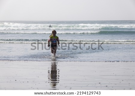 A young girl running on the shore of the Pacific Ocean at Westport Light State Park Beach in Westport, Washington.