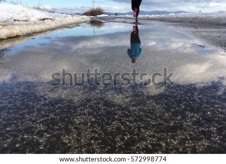 Young girl running in winter nature - reflexion in water