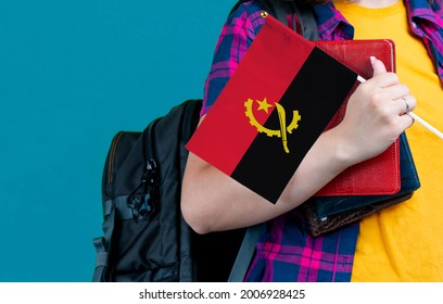 Young Girl With School Stuff Holds In Hand Angola Flag Close Up