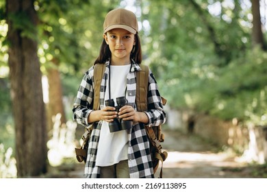 Young girl scout exploring parks with rucksuck and binoculars - Powered by Shutterstock