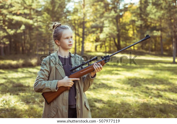 Young girl\
shooting from the air rifle in the\
forest