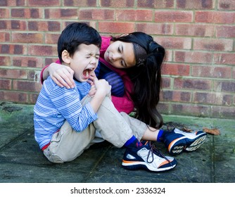 A Young Girl Showing Compassion To Her Little Brother After He Trips Over And Hurt His Leg.