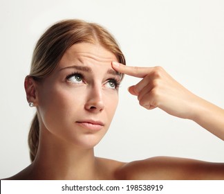 Young Girl Showing With Finger Her First Wrinkle In Forehead