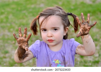 Young Girl Shows Off Her Muddy Hands.