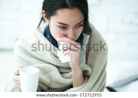 Young girl sick in bed with temperature drinks hot 