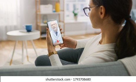 Young Girl Sick At Home Using Smartphone To Talk To Her Doctor Via Video Conference Medical App. Woman Checks Possible Symptoms With Professional Physician, Using Online Video Chat Application