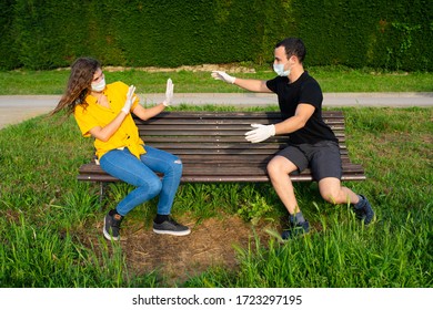 Young Girl Signaling To Stay Away From Boy. Keeping Social Distance Wearing Mask And Gloves. 