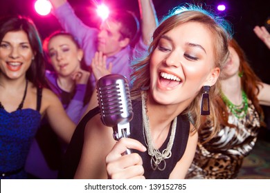 Young girl singing into  microphone at  party - Powered by Shutterstock