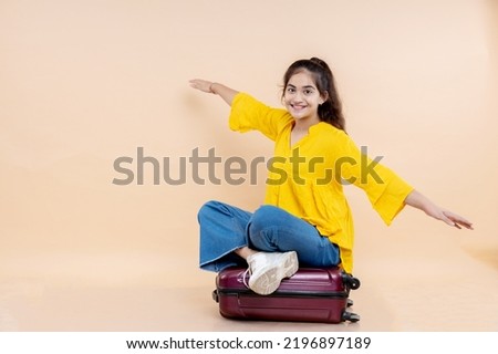 young girl siting on suitcase 