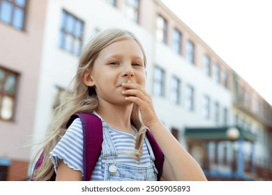 A young girl sits alone in the schoolyard, face in hands, showing sadness and stress - Powered by Shutterstock