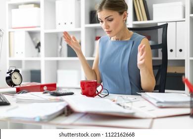 A young girl sits at a table in her office and spread her arms out to the sides. - Shutterstock ID 1122162668