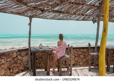 Young girl sitting in a beach bar, looking on a blue lagoon, Zanzibar, Tanzania