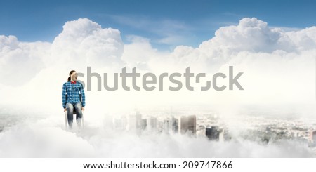 Young girl sitting in chair high in sky