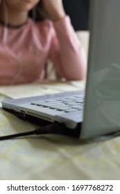 Young Girl Sitting At The Dining Table With Laptop At Home Schooling, Online Virtual Classroom Video Conference, Distant Education. Active Participation At The Lesson With Earphones, Doing Homework.