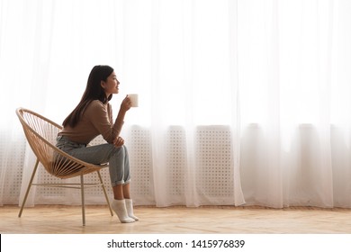 Young Girl Sitting In Modern Chair, Enjoying Coffee In Front Of Window, Side View - Shutterstock ID 1415976839