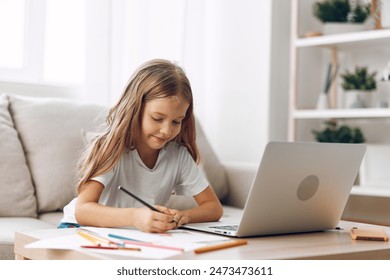 Young girl sitting on couch with laptop and pencil, engaged in online learning or creative work - Powered by Shutterstock