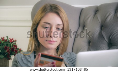 Young girl sitting on the couch purchases via the Internet. Static