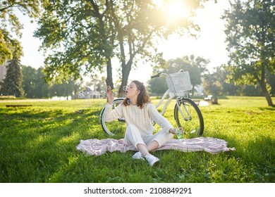 A young girl sitting on the grass and having fun making bubbles