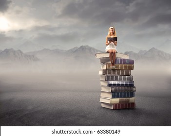 Young Girl Sitting On A Stack Of Books And Reading