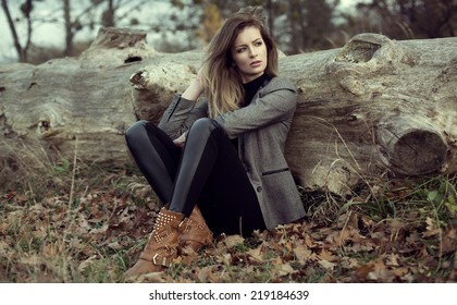 Young Girl Sitting Outdoor In Autumn Scenery