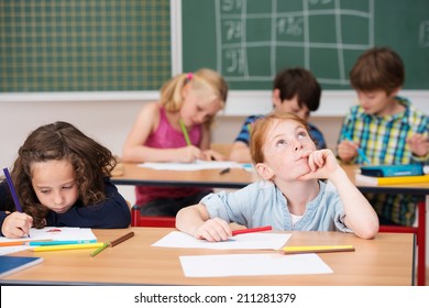 Young Girl Sitting Thinking In Class At School Sitting At Her Desk With A Friend Staring Up Into The Air With A Contemplative Expression