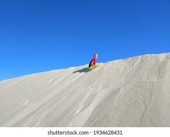 Young Girl Sledding On Sand Dune