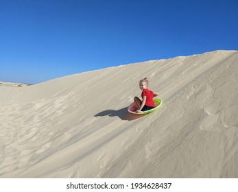 Young Girl Sledding On Sand Dune