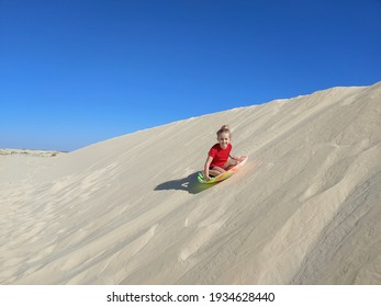 Young Girl Sledding On Sand Dune