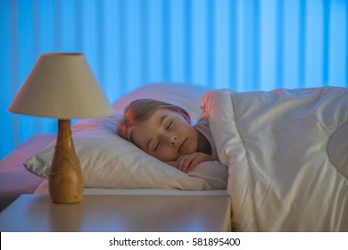 The Young Girl Sleeping On The Bed. Evening Night Time