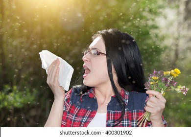 Young girl sneezing and holding paper tissue in one hand and flower bouquet in other. Allergies concept