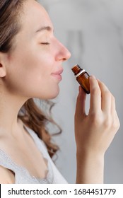 A young girl sniffes essential aromatic oil. Bright home bathroom. Relax, aromatherapy, aromapsychology.