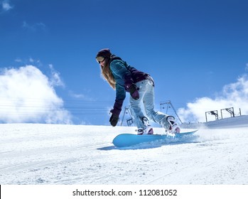 Young Girl Snowboarder In Motion On Snowboard In Mountains