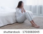 Young girl spending afternoon sitting on bedroom floor, crying because of hurt feelings, closing face with palms, looking miserable and desperate