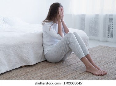 Young Girl Spending Afternoon Sitting On Bedroom Floor, Crying Because Of Hurt Feelings, Closing Face With Palms, Looking Miserable And Desperate