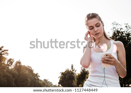 Similar – Woman with earphones listening music in smartphone